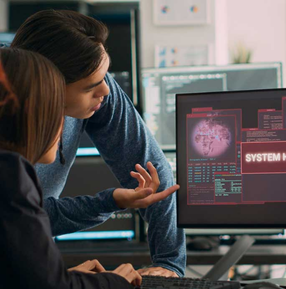 Two IT professionals studying cybersecurity data on a computer screen.